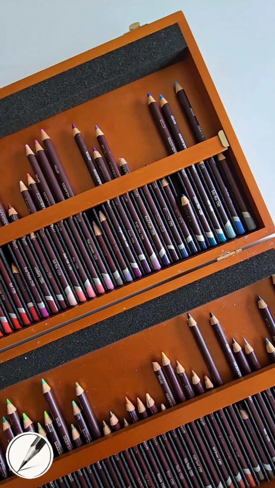 A wooden box of coloured pencils in trays, seen at an angle