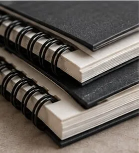 Two black spiral-bound sketchbooks stacked together