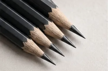Four sharpened black pencils with grey leads on textured paper